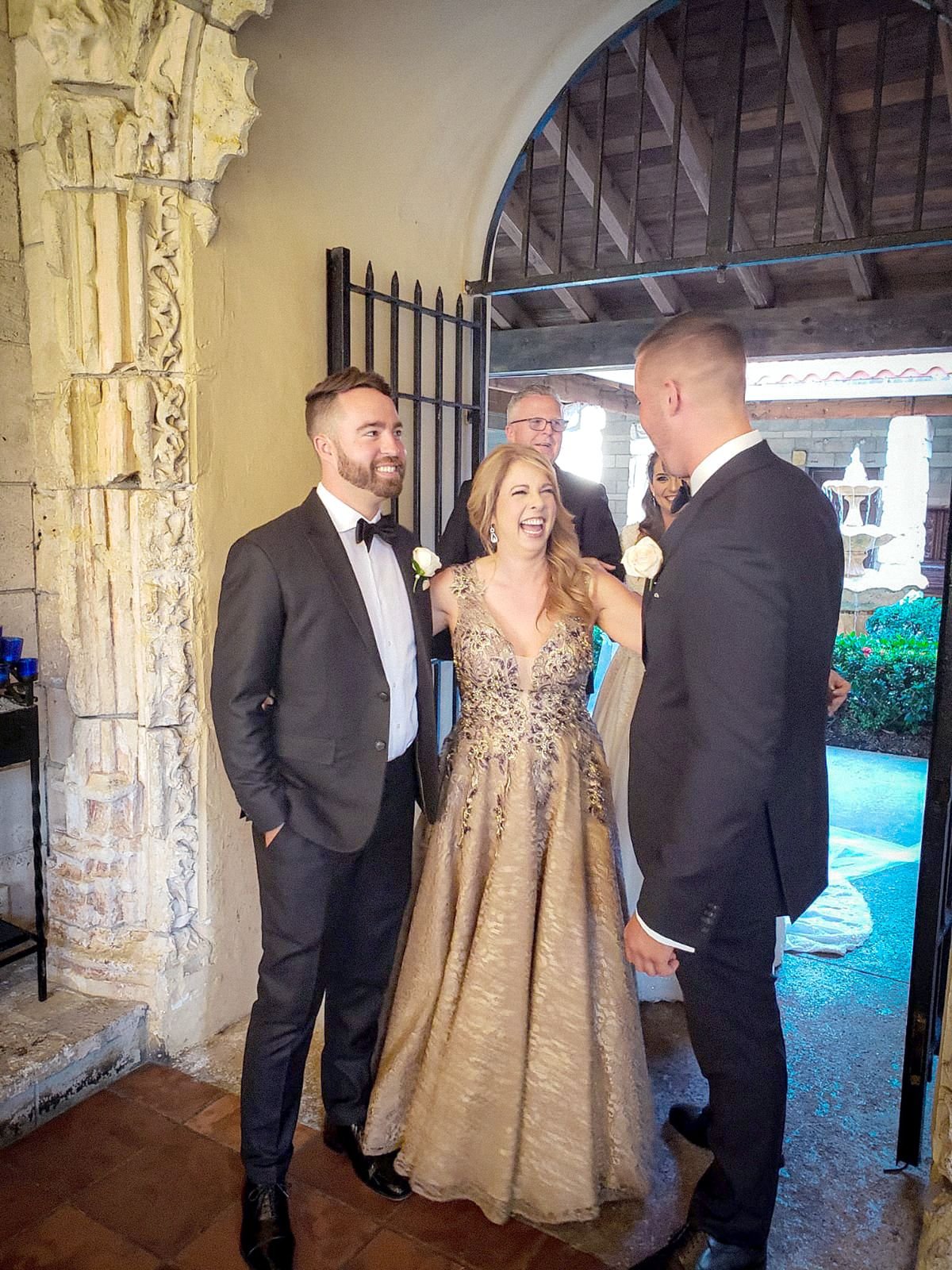 Wedding party laughing at a courtyard archway entrance